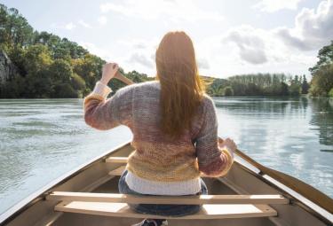 Ragazza naviga il fiume su una barca in legno